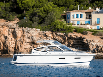 Boat on the ocean in sunny weather next to a cliff with a house on top