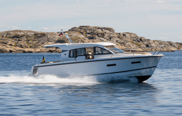 Boat driving fast in the ocean next to a cliff